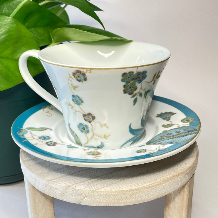 Ceramic cup and saucer with floral design on a wooden stool