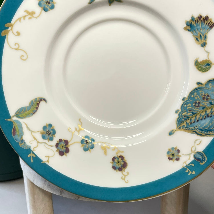Decorative plate with floral and paisley patterns on a stand