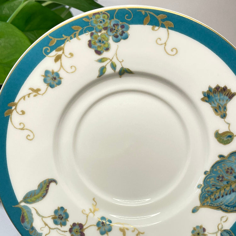 White saucer with blue floral and paisley design on a white background