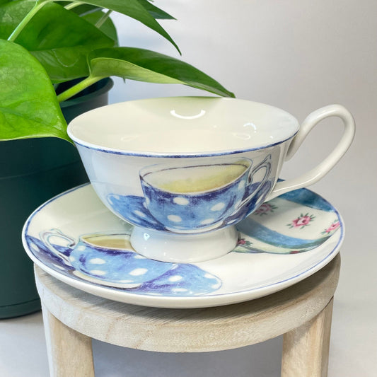 Ceramic teacup and saucer with blue polka dot design on a small wooden stool.