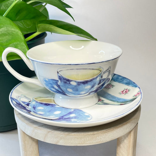 Ceramic teacup and saucer with blue polka dot design on a small wooden stool.