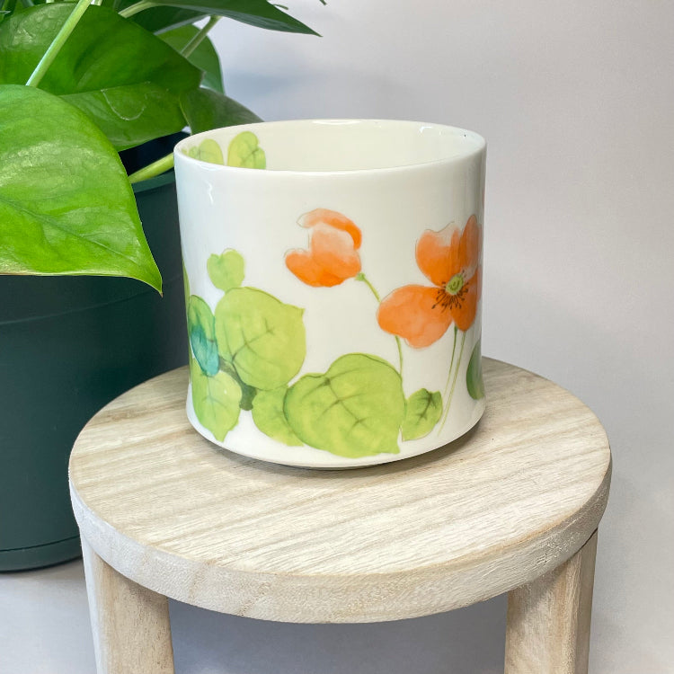 Decorative pot with floral design on a wooden stool